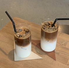 two drinks are sitting on a wooden table