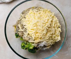 a glass bowl filled with cheese and broccoli