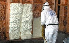 a man in white coveralls standing next to a pile of sheep's wool