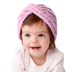 a baby girl wearing a pink hat and smiling at the camera with her hands on her hips