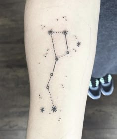 a woman's arm with a small zodiac sign tattoo on the left side of her leg