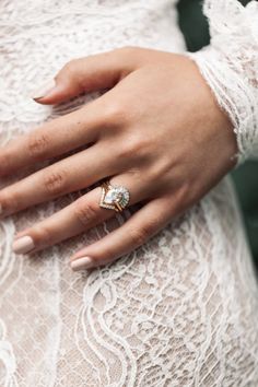 a close up of a person's hand wearing an engagement ring