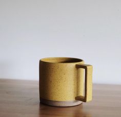 a yellow mug sitting on top of a wooden table