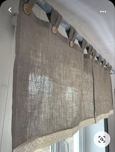 a close up of a curtain with buttons on the top and bottom, in front of a window