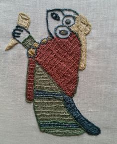 a close up of a embroidery on a piece of cloth with a person holding a knife