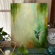 a painting of a hummingbird in flight on a green and yellow background next to a clock