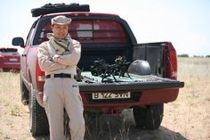 a man standing in the back of a red truck