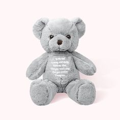 a gray teddy bear sitting on top of a white floor next to a pink wall