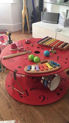 a red table with musical instruments on it in the middle of a living room area