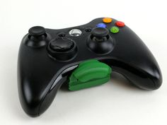 a close up of a video game controller on a white surface with colored buttons and a green cord