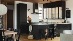 an open kitchen and dining room with black cabinets, white walls and wood floors is shown