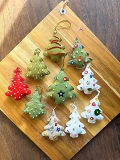 a wooden cutting board topped with lots of christmas trees ornament ornaments on top of a table