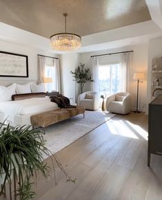 a bedroom with white walls and wood flooring has a chandelier hanging from the ceiling