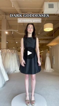 a woman standing in front of dresses on display