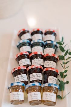 small jars filled with jam sit on a white plate next to a green plant and leaves