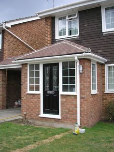 a brick house with a black front door and white trim around the windows, along with an awning