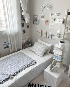 a white bedroom with lots of pictures on the wall and a bed covered in blankets