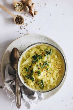 a white bowl filled with pasta on top of a table next to spoons and garlic