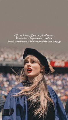 a woman with long hair wearing a graduation cap and gown in front of a stadium