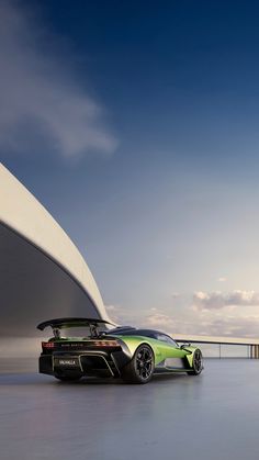 a green sports car parked in front of a white building with a large window on the side