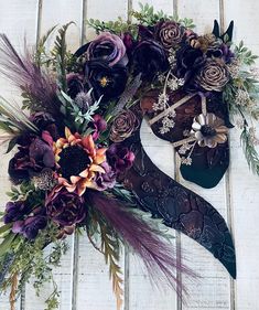 an arrangement of flowers and feathers on a white wooden surface with a pair of shoes