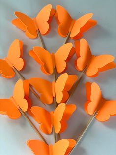 there are many orange butterflies on the stick and one is cut out to look like hearts