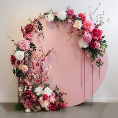 an arrangement of flowers on a pink circular wall in front of a white wall and floor