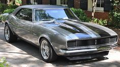 an old muscle car parked in front of a house