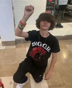 a young boy is sitting on the floor with his arm in the air