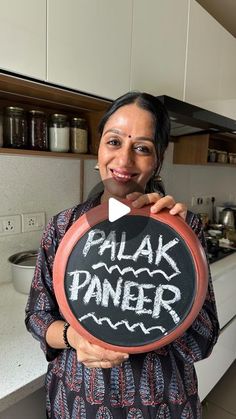 a woman holding up a chalk board with the words palak paneer written on it