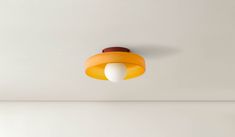 an orange and white light hanging from the ceiling in a room with no one around it