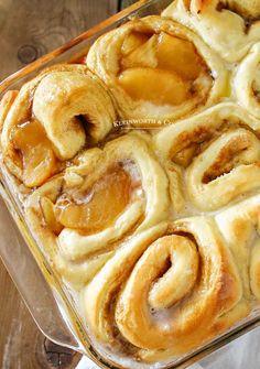 a glass dish filled with cinnamon rolls on top of a wooden table