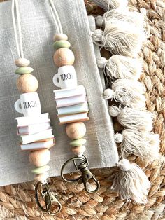 two wooden beads with tassels are hanging from a keychain on a table