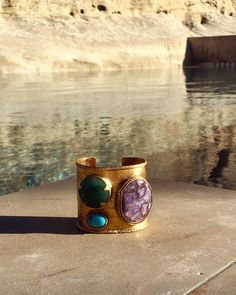 This elegant cuff is made of 24k gold-plated brass with a trio of Amethyst, Turquoise and green Agate. Intricate carved Aztec finished border and twisted stone setting.  All gemstones are natural and therefore will vary in color/pattern. 2.5 inches long Amethyst is a meditative and calming stone which works in the emotional, spiritual, and physical planes to provide calm, balance, patience, and peace. Turquoise is a protective stone and has been used throughout the ages for protective amulets. T Calming Stones, Stone Setting, Green Agate, Inner Strength, Stone Settings, Color Patterns, Cuff Bracelets, Amethyst, Spirituality