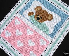 a teddy bear is on top of a crocheted blanket with hearts and dots