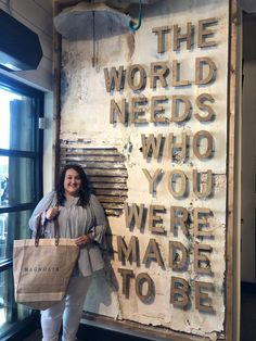 a woman standing in front of a sign that says the world needs who you were made to be