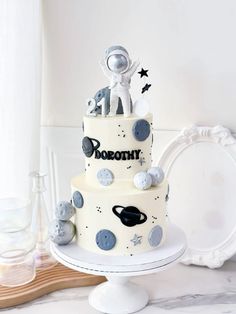 a three tiered cake with an astronaut theme on the top and stars around it