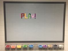 the word play spelled out with colored crayons in front of a white wall