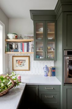 a kitchen with green cabinets and white counter tops, along with a stainless steel oven