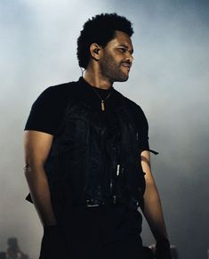 a man standing in front of a crowd with his head turned to the side wearing ear buds