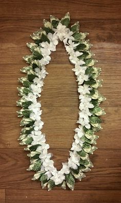 white flowers and green leaves are arranged on a wooden surface in the shape of an o