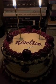 a cake with two candles on top of it and the words nineteen spelled in red