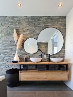 a bathroom with two round mirrors above the sinks and a black trash can in front of it