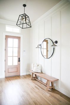 a wooden bench sitting in front of a door next to a mirror on the wall