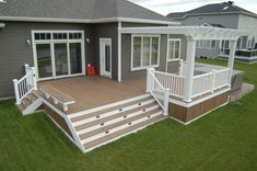 a deck with steps leading up to the front door and patio area on top of it