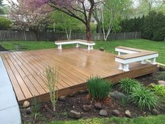 a wooden deck with benches in the middle of it and flowers on the ground next to it