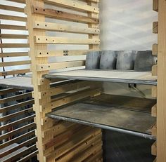 the shelves are made out of pallets and have metal trays on each shelf