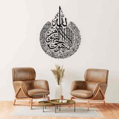 two chairs and a coffee table in front of a wall with an arabic calligraphy on it