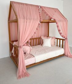 a canopy bed with pink curtains and pillows