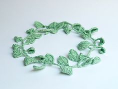 green crocheted leaves arranged in a circle on a white surface with space for text